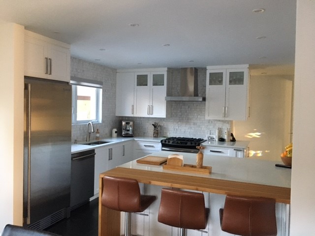 Mid-sized transitional l-shaped ceramic tile and gray floor enclosed kitchen photo in Montreal with an undermount sink, shaker cabinets, white cabinets, wood countertops, multicolored backsplash, mosaic tile backsplash, stainless steel appliances and an island
