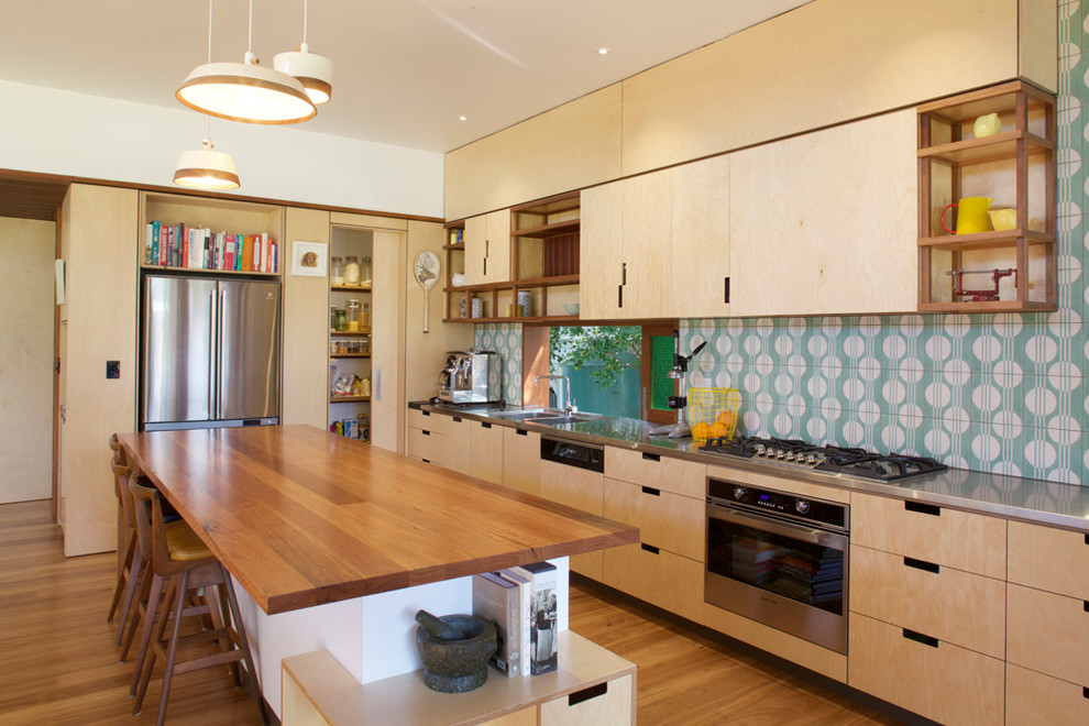 Medium sized contemporary galley kitchen/diner in Brisbane with a double-bowl sink, light wood cabinets, wood worktops, green splashback, cement tile splashback, stainless steel appliances, light hardwood flooring, an island and flat-panel cabinets.