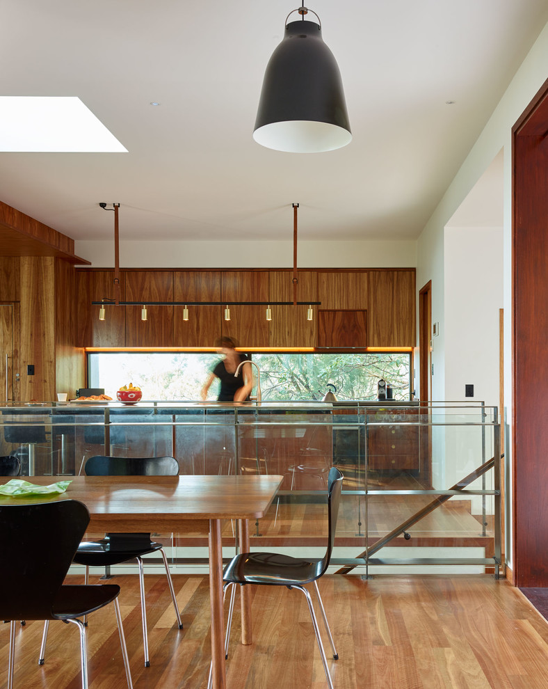 Ispirazione per una cucina design di medie dimensioni con ante in legno scuro, top in cemento, elettrodomestici neri e pavimento in legno massello medio