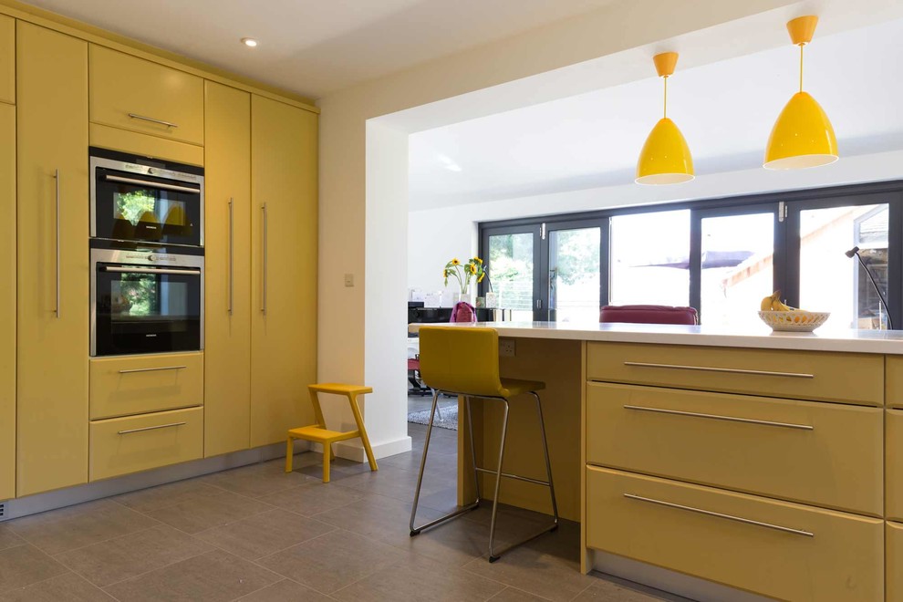 Design ideas for a large classic u-shaped kitchen/diner in West Midlands with an integrated sink, raised-panel cabinets, yellow cabinets, marble worktops, white splashback, stainless steel appliances, porcelain flooring and a breakfast bar.