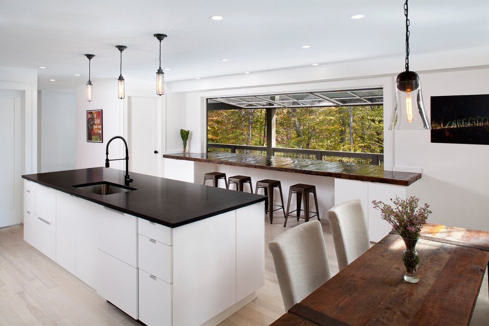 Eat-in kitchen - farmhouse light wood floor eat-in kitchen idea in Richmond with an undermount sink, flat-panel cabinets, white cabinets, an island and black countertops