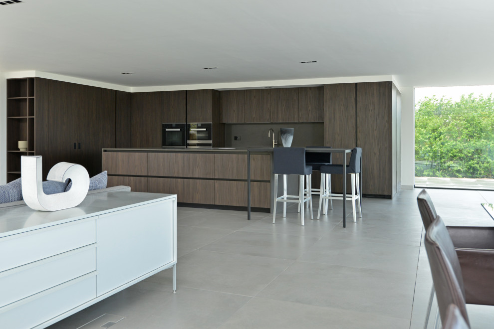 Immagine di una cucina minimalista con ante lisce, ante in legno bruno, paraspruzzi grigio, elettrodomestici in acciaio inossidabile, pavimento grigio e top grigio