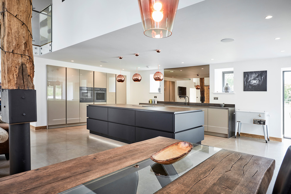 Photo of a large contemporary l-shaped open plan kitchen in Other with a built-in sink, flat-panel cabinets, black cabinets, engineered stone countertops, multi-coloured splashback, mirror splashback, coloured appliances, concrete flooring, an island, grey floors, black worktops and exposed beams.
