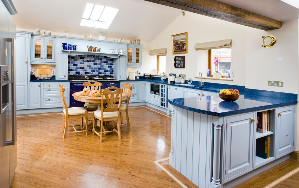 На фото: кухня в стиле кантри с обеденным столом, монолитной мойкой, фасадами с декоративным кантом, синими фасадами, синим фартуком, цветной техникой и паркетным полом среднего тона