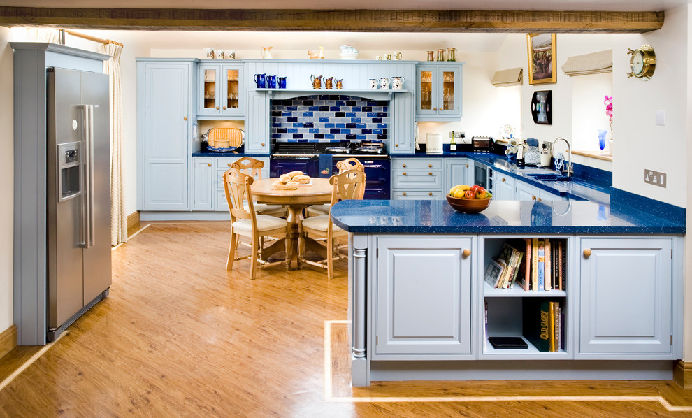 Foto de cocina comedor de estilo de casa de campo con fregadero integrado, armarios con rebordes decorativos, puertas de armario azules, salpicadero azul, electrodomésticos de colores y suelo de madera en tonos medios