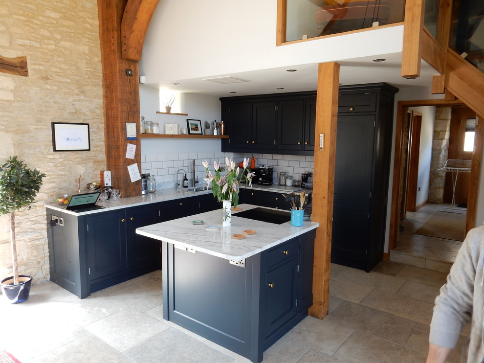 Design ideas for an expansive rustic l-shaped open plan kitchen in Wiltshire with a submerged sink, recessed-panel cabinets, blue cabinets, marble worktops, ceramic splashback, integrated appliances, ceramic flooring, an island and white floors.