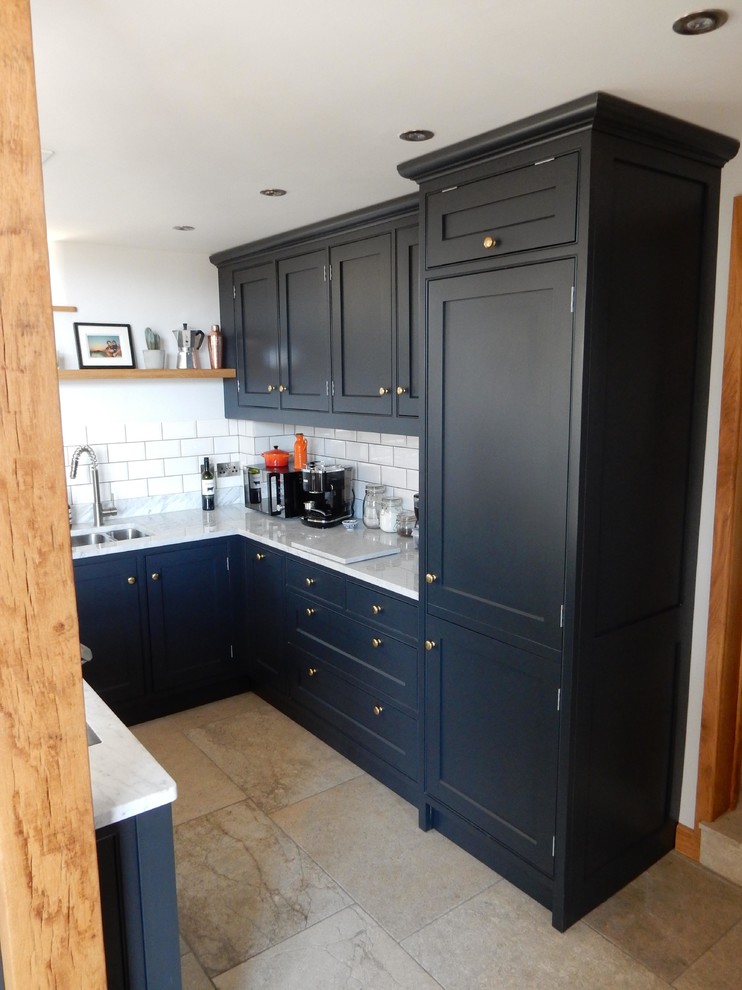 This is an example of an expansive rustic l-shaped open plan kitchen in Wiltshire with a submerged sink, recessed-panel cabinets, blue cabinets, marble worktops, ceramic splashback, integrated appliances, ceramic flooring, an island and white floors.