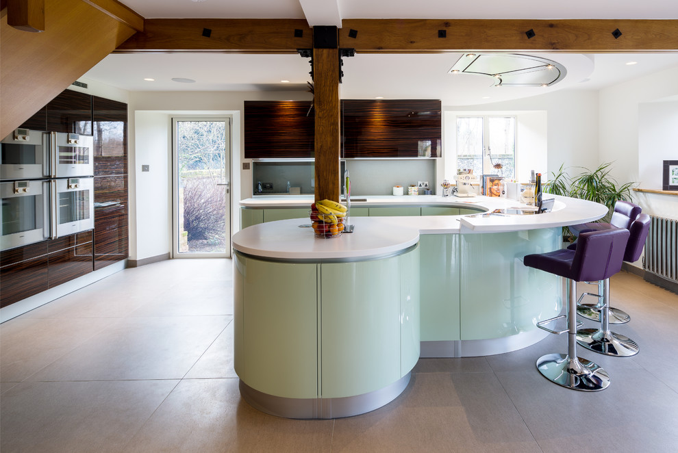 Medium sized contemporary u-shaped kitchen/diner in London with a submerged sink, flat-panel cabinets, green cabinets, composite countertops, glass sheet splashback, stainless steel appliances and a breakfast bar.