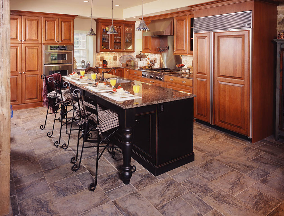Inredning av ett klassiskt avskilt, mellanstort brun brunt l-kök, med en undermonterad diskho, luckor med upphöjd panel, skåp i mellenmörkt trä, granitbänkskiva, brunt stänkskydd, stänkskydd i stenkakel, integrerade vitvaror, en köksö och flerfärgat golv