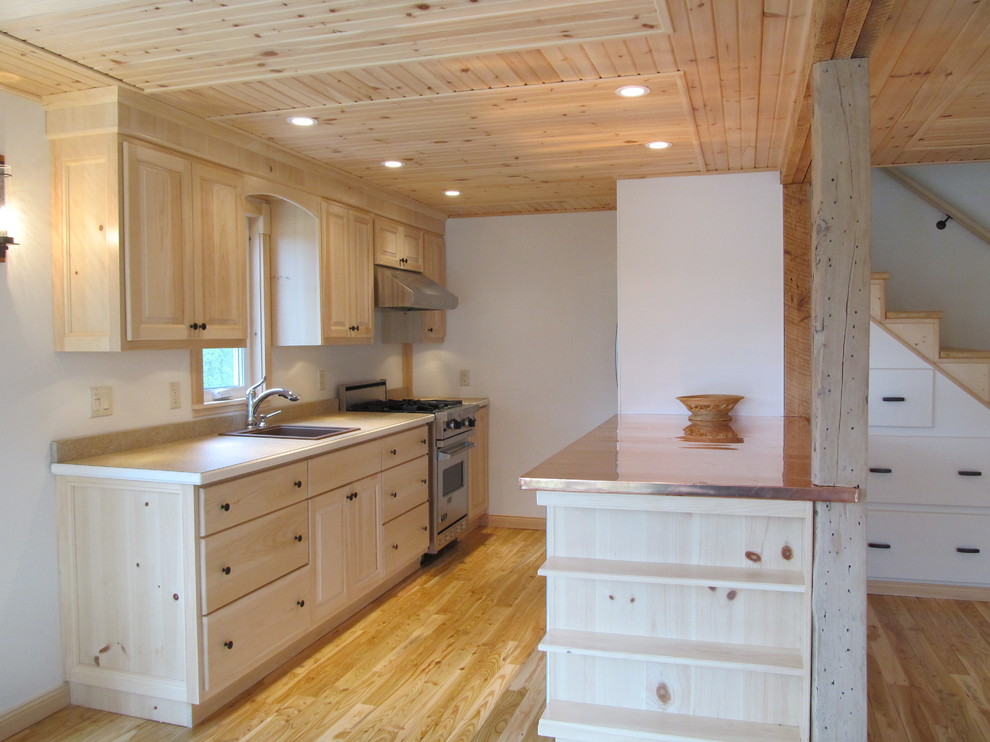 Exempel på ett litet rustikt kök, med ljust trägolv, skåp i ljust trä, bänkskiva i akrylsten, rostfria vitvaror, en nedsänkt diskho, släta luckor och beiget golv