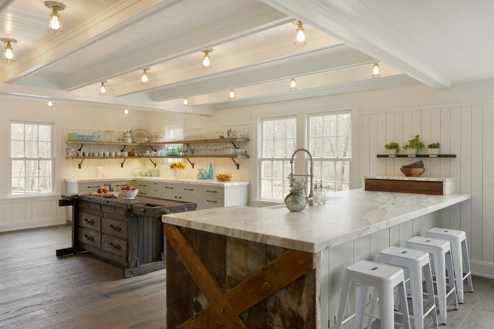 Large elegant u-shaped medium tone wood floor and brown floor eat-in kitchen photo in New York with a farmhouse sink, flat-panel cabinets, green cabinets, marble countertops, white backsplash, paneled appliances, a peninsula and multicolored countertops