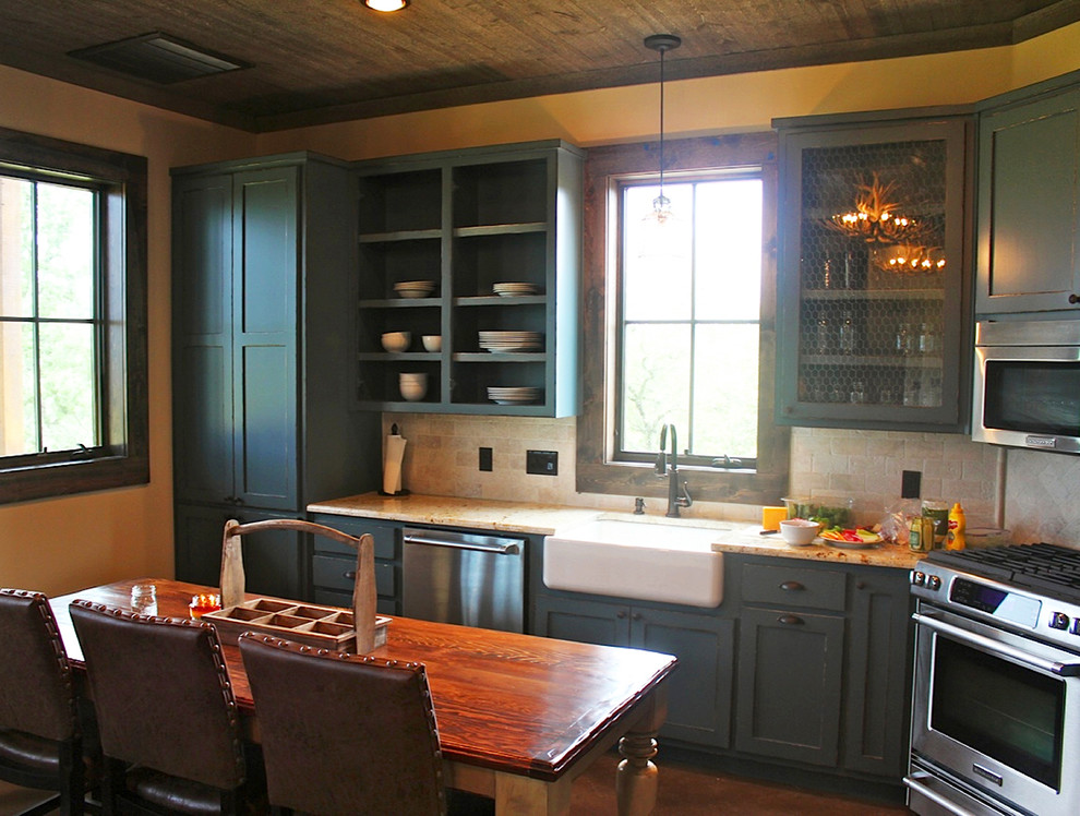 Idéer för mellanstora lantliga kök, med en rustik diskho, luckor med infälld panel, blå skåp, granitbänkskiva, beige stänkskydd, rostfria vitvaror, mellanmörkt trägolv och en köksö