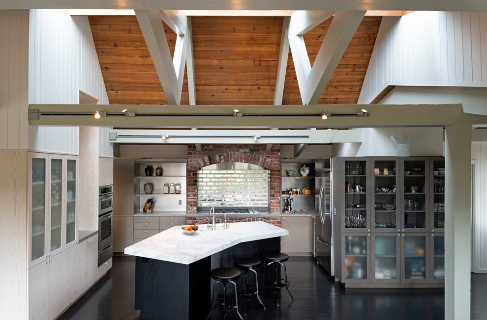 Foto på ett funkis kök, med släta luckor, skåp i ljust trä, stänkskydd med metallisk yta, stänkskydd i tunnelbanekakel och rostfria vitvaror