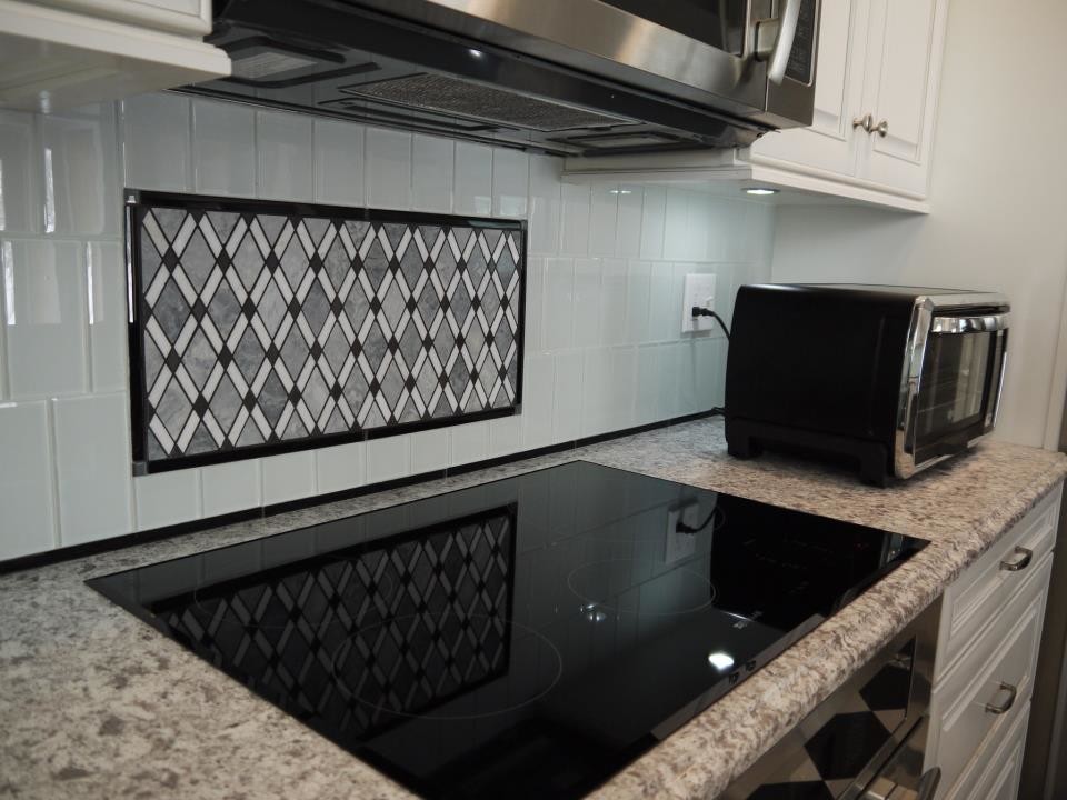 Eat-in kitchen - mid-sized eclectic u-shaped ceramic tile eat-in kitchen idea in Grand Rapids with a farmhouse sink, raised-panel cabinets, white cabinets, quartzite countertops, blue backsplash, stainless steel appliances, glass tile backsplash and no island
