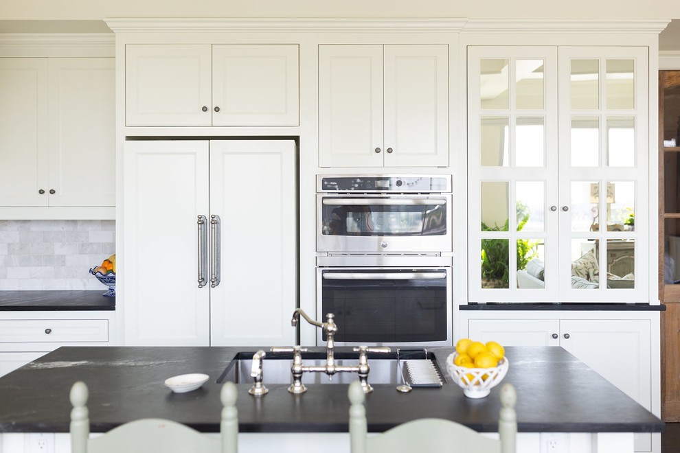 Small classic l-shaped kitchen/diner in Little Rock with a single-bowl sink, flat-panel cabinets, white cabinets, soapstone worktops, white splashback, marble splashback, integrated appliances, concrete flooring, an island, grey floors and green worktops.