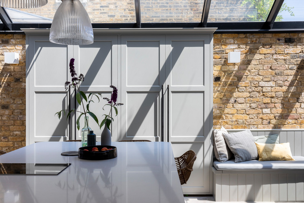 Klassische Wohnküche mit Schrankfronten im Shaker-Stil, Mineralwerkstoff-Arbeitsplatte, Kücheninsel und grauem Boden in London