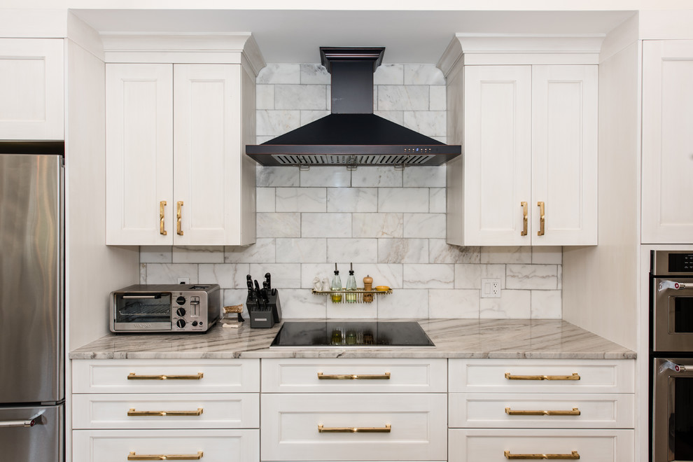 Example of a large transitional u-shaped medium tone wood floor open concept kitchen design in DC Metro with an undermount sink, recessed-panel cabinets, white cabinets, marble countertops, gray backsplash, subway tile backsplash, stainless steel appliances and an island