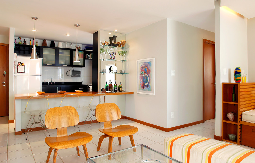 На фото: кухня-гостиная в современном стиле с стеклянными фасадами, белой техникой и барной стойкой с