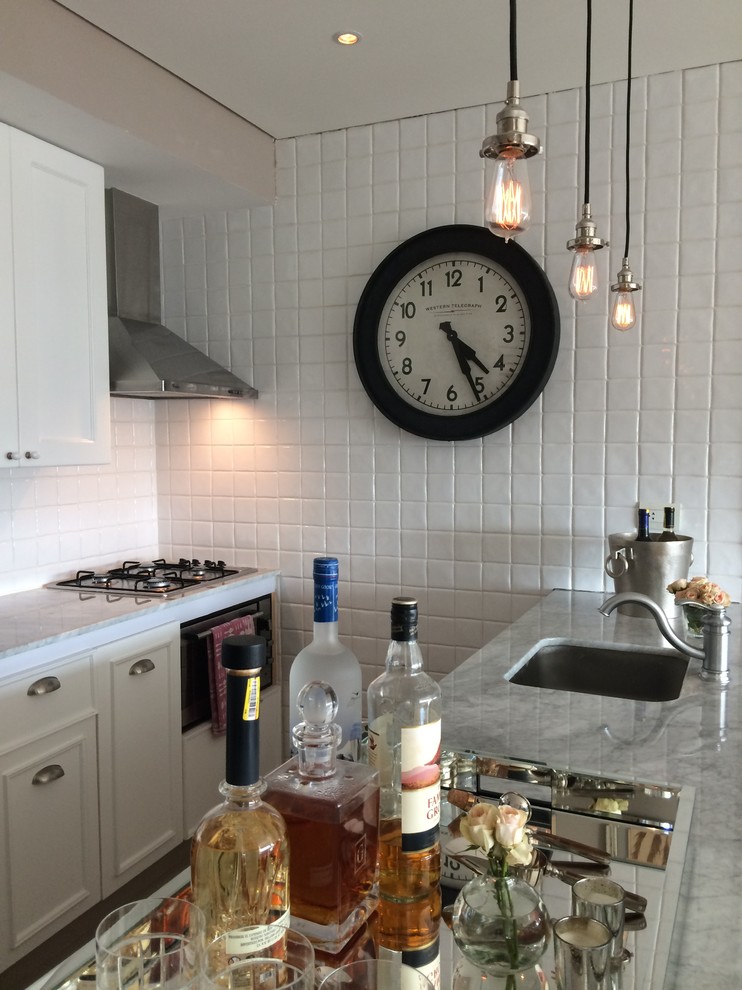 Photo of a small urban single-wall kitchen/diner in Other with a single-bowl sink, recessed-panel cabinets, white cabinets, marble worktops, white splashback, ceramic splashback, black appliances, porcelain flooring and no island.