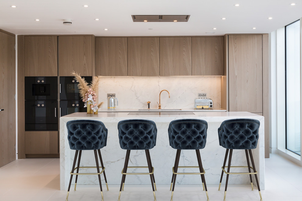 Design ideas for a contemporary kitchen in London with a submerged sink, flat-panel cabinets, light wood cabinets, white splashback, stone slab splashback, black appliances, an island, white floors, white worktops and marble worktops.