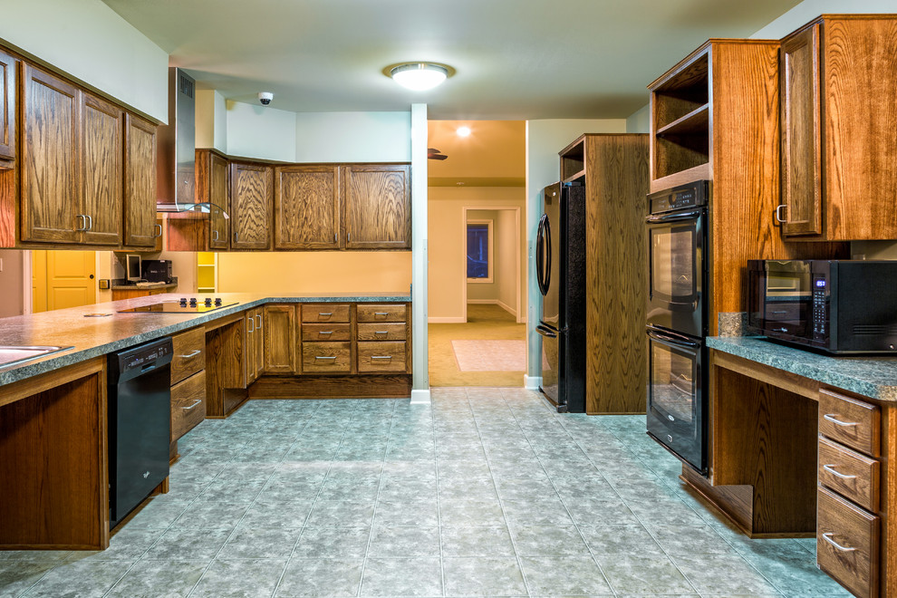 Inspiration for a huge timeless galley linoleum floor and blue floor enclosed kitchen remodel in Detroit with a drop-in sink, recessed-panel cabinets, dark wood cabinets, granite countertops, black appliances and no island