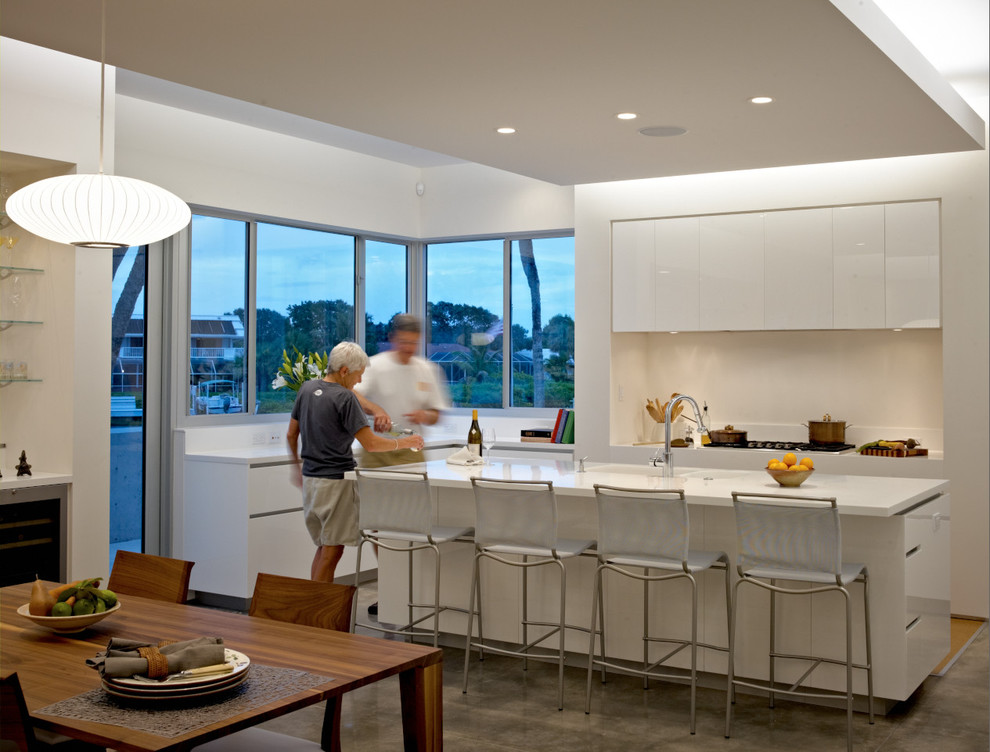 Moderne Wohnküche mit flächenbündigen Schrankfronten, weißen Schränken und Küchenrückwand in Weiß in Sonstige