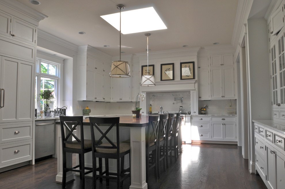 Mid-sized elegant u-shaped dark wood floor and brown floor open concept kitchen photo in Cincinnati with flat-panel cabinets, white cabinets, wood countertops, white backsplash, subway tile backsplash, stainless steel appliances, an island and a farmhouse sink