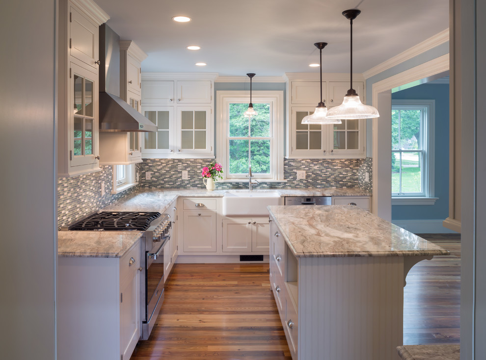 Example of a country l-shaped medium tone wood floor eat-in kitchen design in Providence with a farmhouse sink, recessed-panel cabinets, white cabinets, multicolored backsplash, stainless steel appliances, marble countertops, matchstick tile backsplash and an island