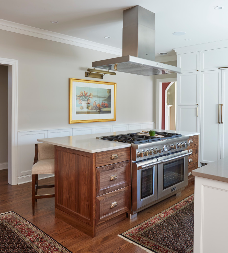 Exempel på ett stort klassiskt kök, med en rustik diskho, luckor med infälld panel, skåp i mellenmörkt trä, bänkskiva i kvartsit, vitt stänkskydd, stänkskydd i porslinskakel, integrerade vitvaror, mörkt trägolv, en köksö och brunt golv
