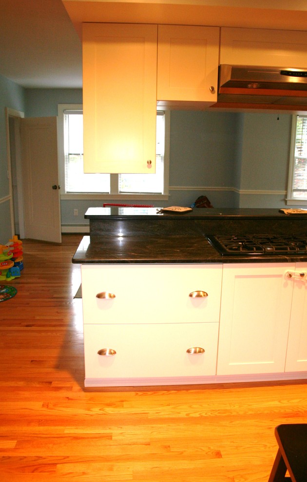 This is an example of a large classic l-shaped kitchen/diner in Providence with an island, shaker cabinets, white cabinets, granite worktops, blue splashback, stainless steel appliances, a built-in sink and medium hardwood flooring.