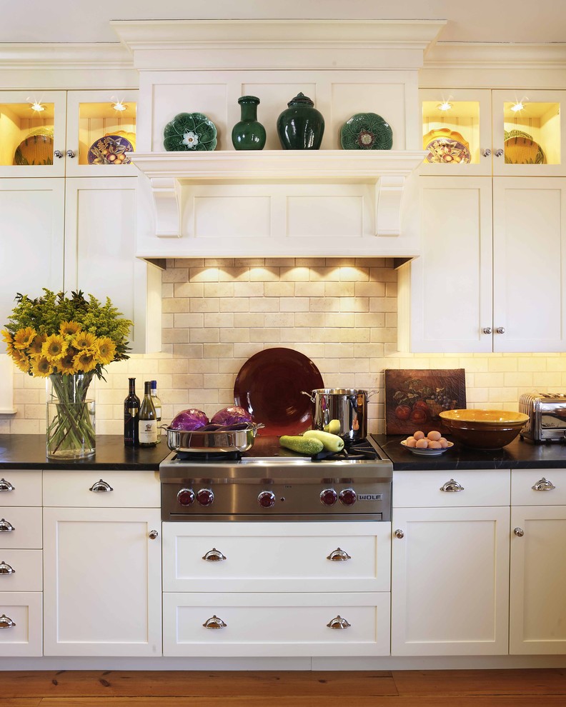 Example of a classic kitchen design in Boston with shaker cabinets, white cabinets, beige backsplash, stainless steel appliances, soapstone countertops and limestone backsplash