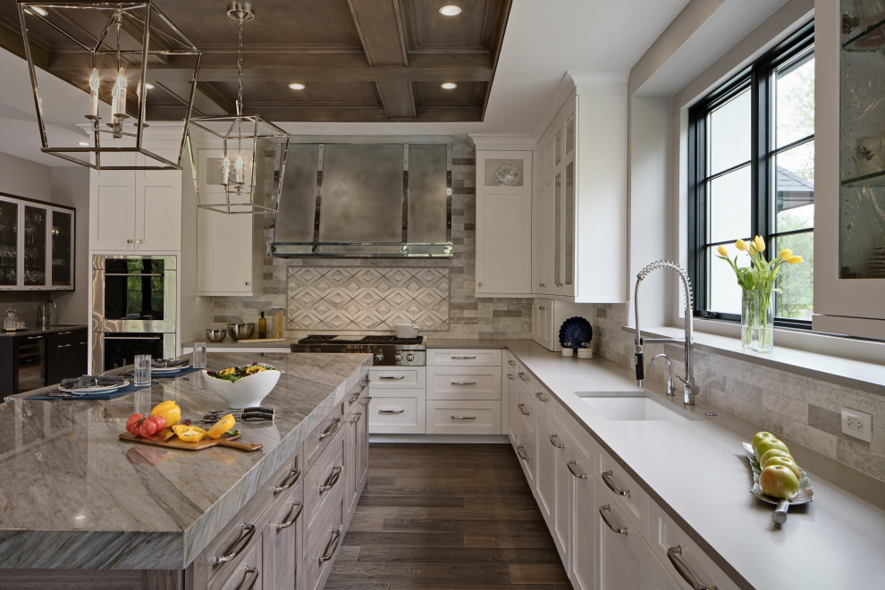 Photo of a classic u-shaped kitchen in Chicago with a submerged sink, shaker cabinets, white cabinets, grey splashback, stainless steel appliances, dark hardwood flooring, an island, brown floors and grey worktops.