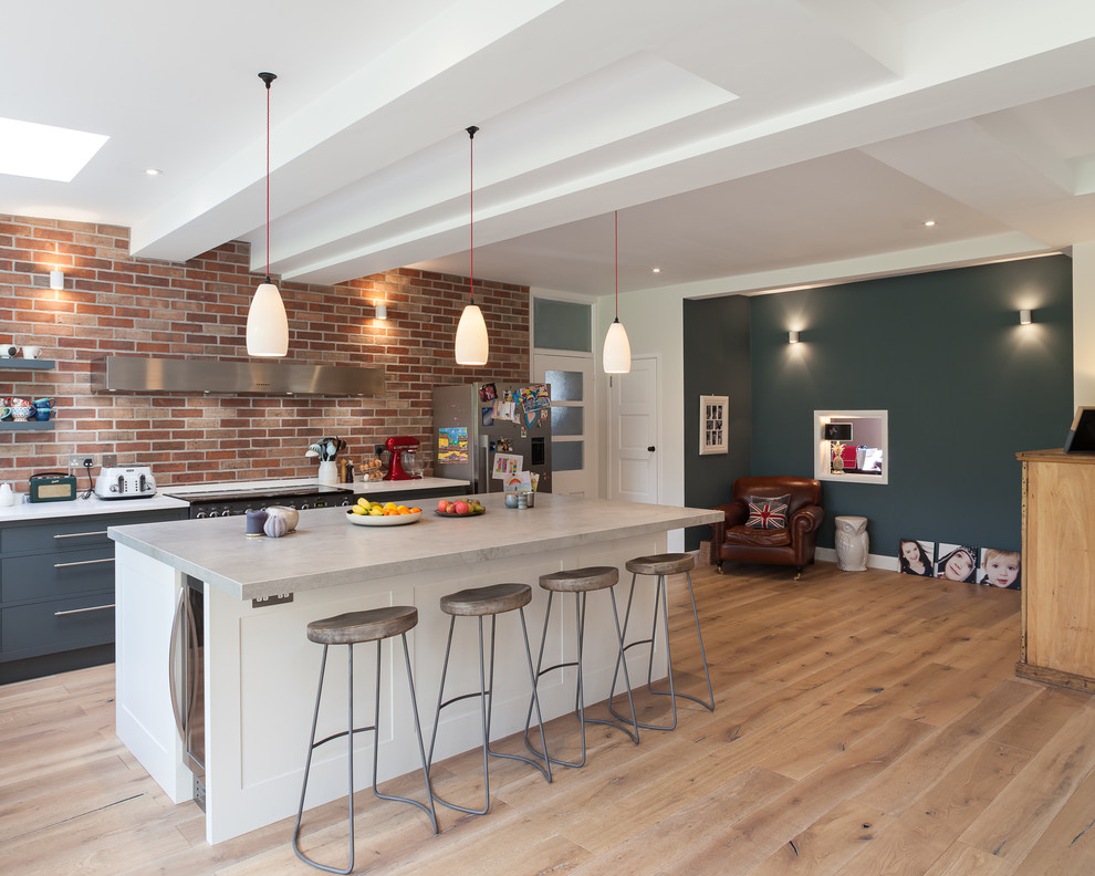 This is an example of a large contemporary l-shaped kitchen/diner in London with flat-panel cabinets, grey cabinets, integrated appliances, medium hardwood flooring and a breakfast bar.