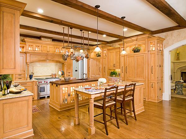 Amerikansk inredning av ett stort kök, med en undermonterad diskho, luckor med upphöjd panel, skåp i ljust trä, granitbänkskiva, beige stänkskydd, stänkskydd i stenkakel, integrerade vitvaror, mellanmörkt trägolv och flera köksöar
