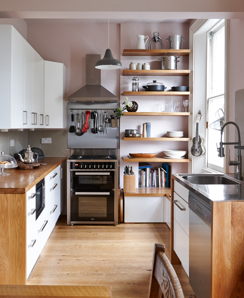 Kitchen - small contemporary medium tone wood floor kitchen idea in London with flat-panel cabinets, white cabinets, wood countertops, gray backsplash, porcelain backsplash, no island and black appliances