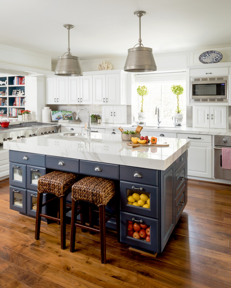 Large elegant u-shaped medium tone wood floor and brown floor enclosed kitchen photo in Los Angeles with an undermount sink, raised-panel cabinets, white cabinets, gray backsplash, porcelain backsplash, stainless steel appliances, an island and white countertops