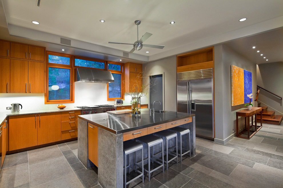 Cette image montre une cuisine design en L et bois brun fermée avec un plan de travail en inox, une crédence blanche, un électroménager en acier inoxydable et un placard à porte plane.