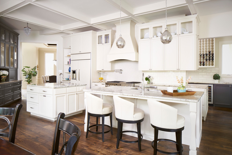 Foto på ett medelhavsstil kök och matrum, med en undermonterad diskho, luckor med infälld panel, vita skåp, vitt stänkskydd, mörkt trägolv, flera köksöar, brunt golv och integrerade vitvaror
