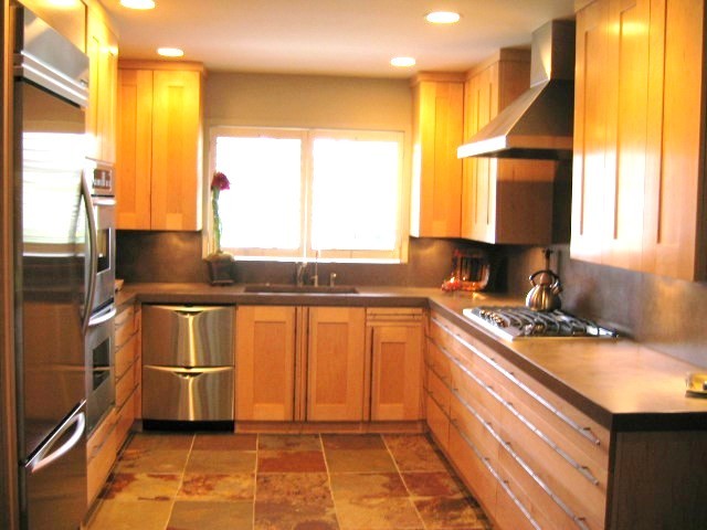 Modern inredning av ett litet kök, med en undermonterad diskho, skåp i shakerstil, skåp i mellenmörkt trä, bänkskiva i betong, grått stänkskydd, stänkskydd i cementkakel, rostfria vitvaror och skiffergolv