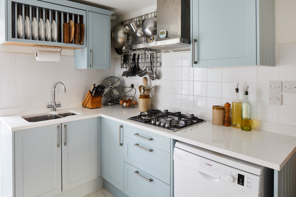 Photo of a small traditional l-shaped kitchen in London with a submerged sink, shaker cabinets, blue cabinets, white splashback, white appliances, no island, grey floors and white worktops.