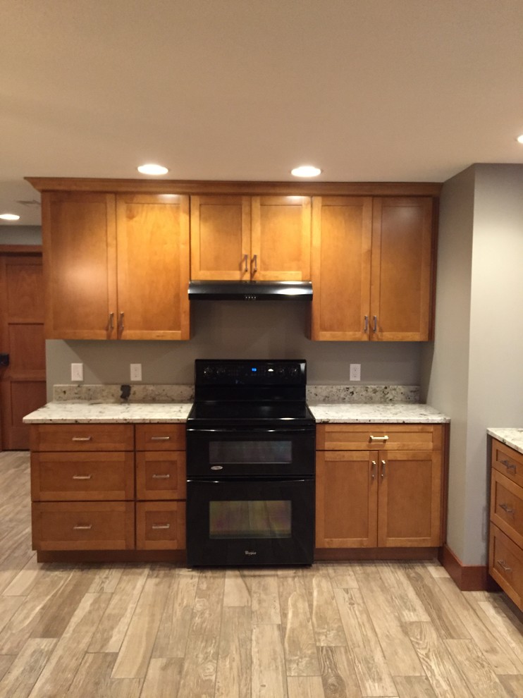 Photo of a medium sized classic u-shaped open plan kitchen in Other with a submerged sink, shaker cabinets, medium wood cabinets, granite worktops, black appliances and an island.