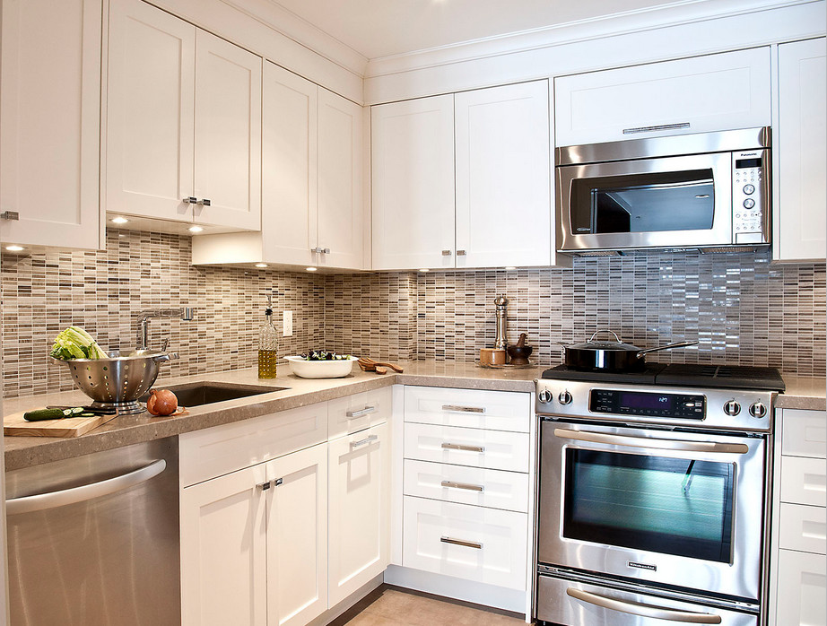Transitional u-shaped porcelain tile enclosed kitchen photo in Toronto with an undermount sink, shaker cabinets, white cabinets, solid surface countertops, stone tile backsplash and stainless steel appliances