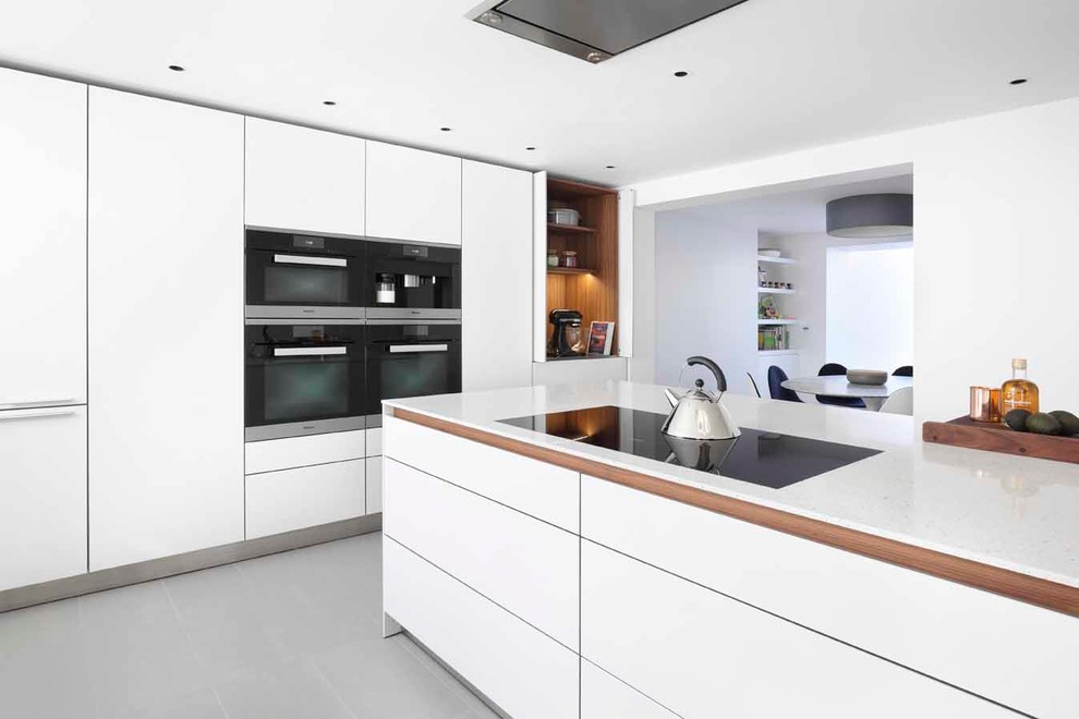 Inspiration for a mid-sized contemporary l-shaped eat-in kitchen remodel in London with white cabinets, laminate countertops, black appliances, an island and flat-panel cabinets