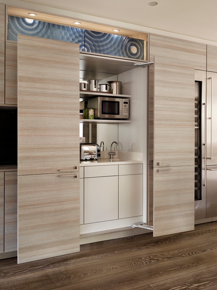 Diseño de cocina actual con armarios con paneles lisos, puertas de armario de madera clara, electrodomésticos de acero inoxidable, suelo de madera oscura y salpicadero con efecto espejo