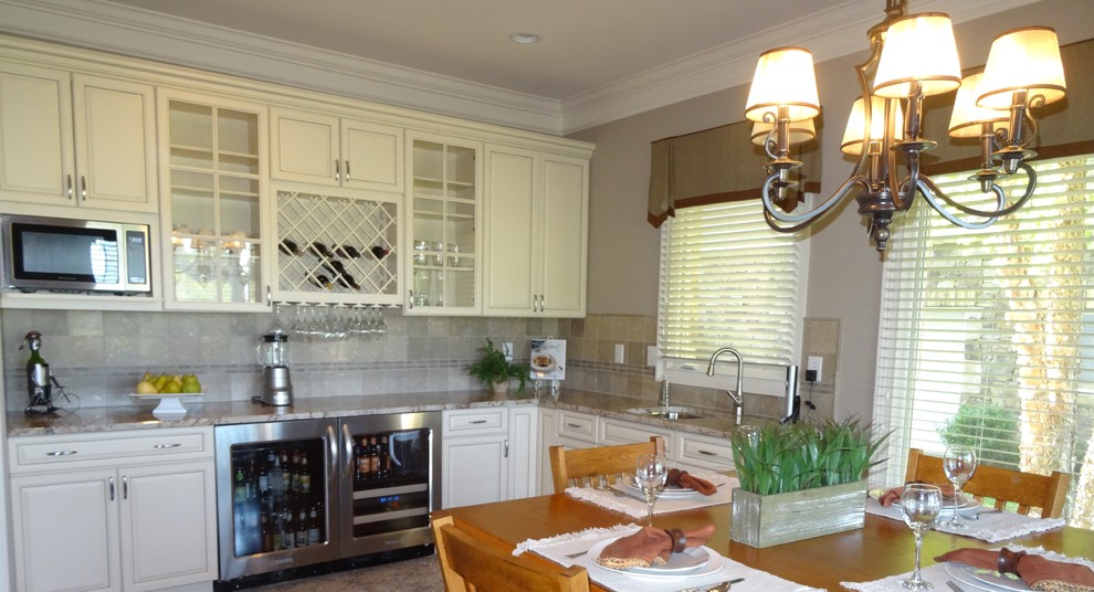 Inredning av ett klassiskt kök, med en undermonterad diskho, vita skåp, granitbänkskiva, grått stänkskydd, stänkskydd i porslinskakel och rostfria vitvaror