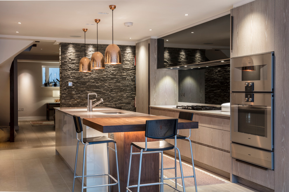 Contemporary galley kitchen in Berkshire with a submerged sink, flat-panel cabinets, grey cabinets, stainless steel appliances, an island and grey floors.