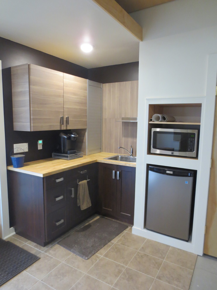Bild på ett avskilt, litet funkis l-kök, med en nedsänkt diskho, skåp i shakerstil, skåp i mörkt trä, träbänkskiva, svart stänkskydd, rostfria vitvaror och travertin golv
