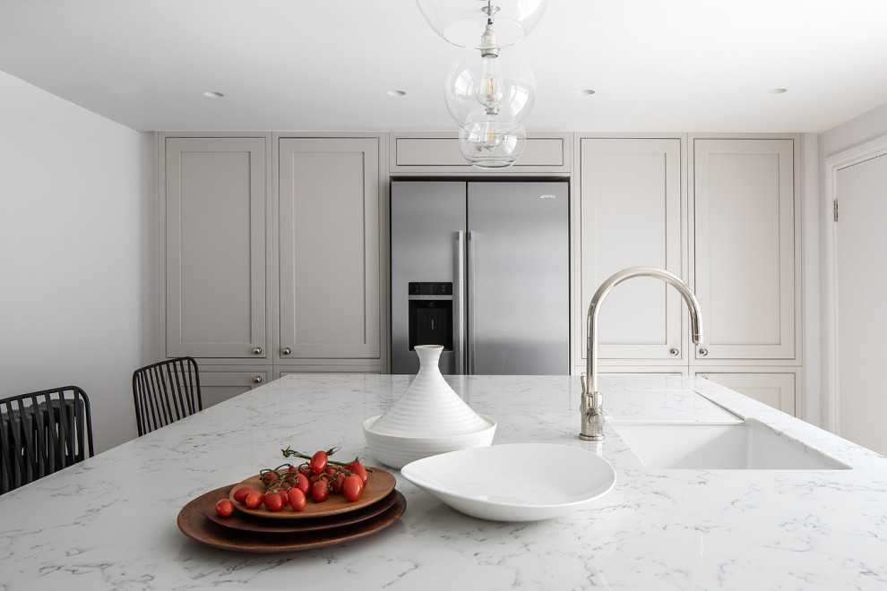 Foto di un cucina con isola centrale classico di medie dimensioni con lavello sottopiano, ante in stile shaker, ante beige e top bianco