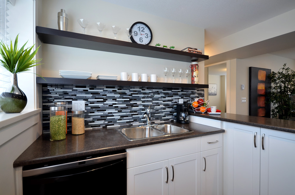 Diseño de cocina actual con fregadero encastrado, armarios estilo shaker, puertas de armario blancas, salpicadero multicolor y electrodomésticos negros