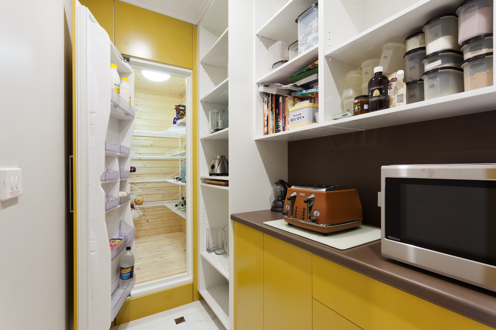 パースにあるモダンスタイルのおしゃれなL型キッチン (フラットパネル扉のキャビネット、黄色いキャビネット、ラミネートカウンター、茶色いキッチンパネル、茶色いキッチンカウンター) の写真